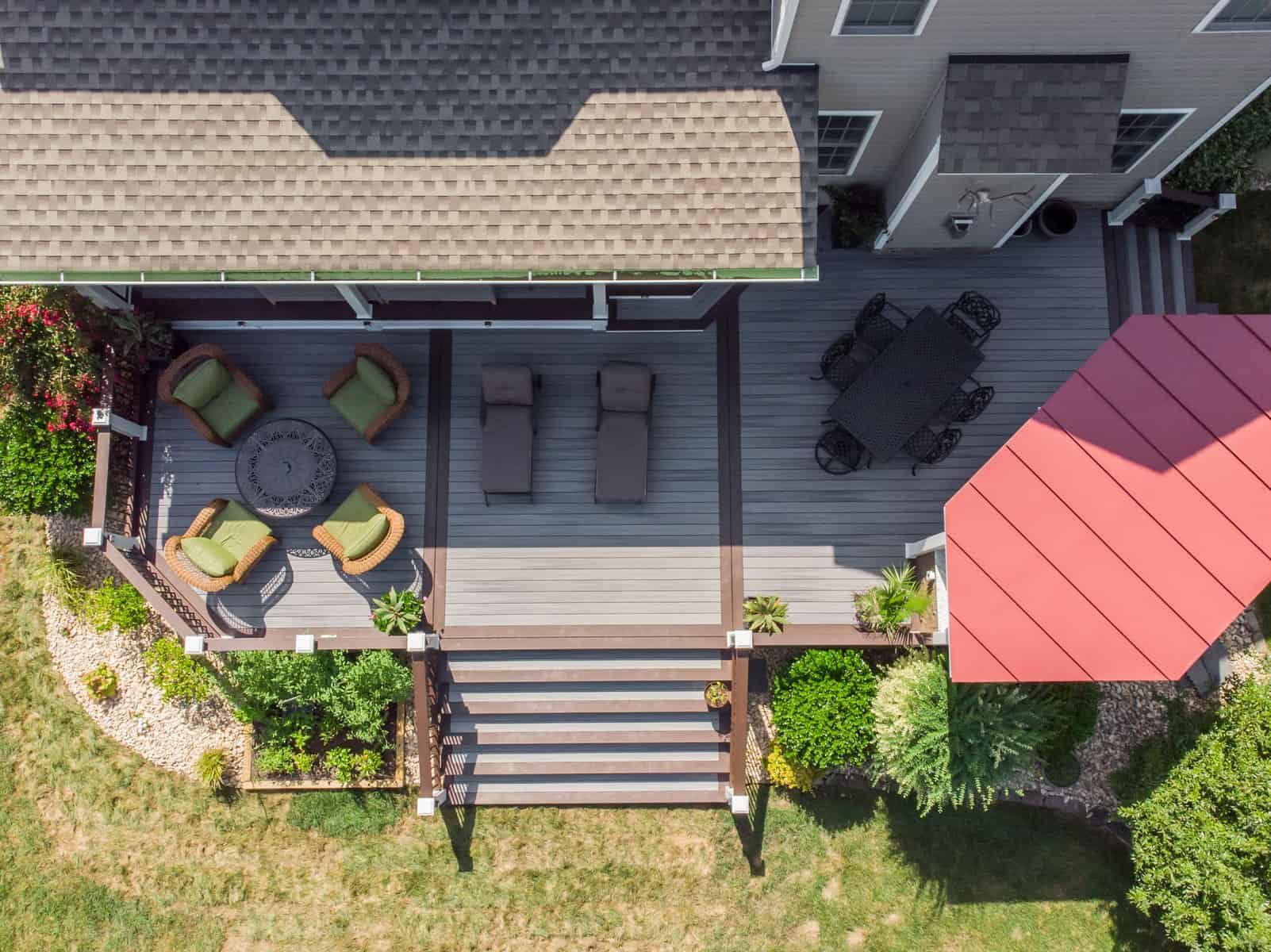 Overhead view of a multi-level deck with outdoor furniture, red awning, and landscaping next to a house.
