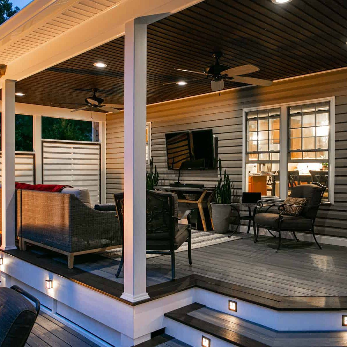 Outdoor covered patio with seating, tv, and recessed lighting.