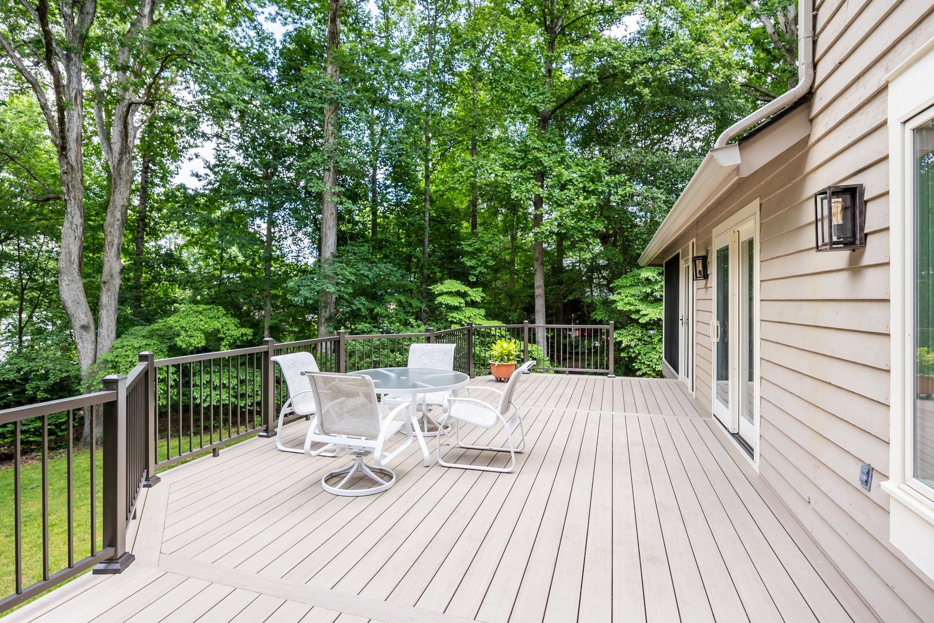 Wooden deck with outdoor dining set, overlooking lush trees.