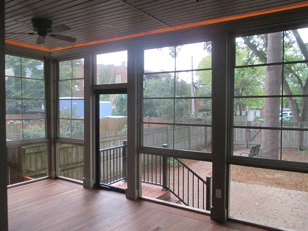 Screened porch with large windows overlooking a backyard and steps. Brown wood floor and ceiling.