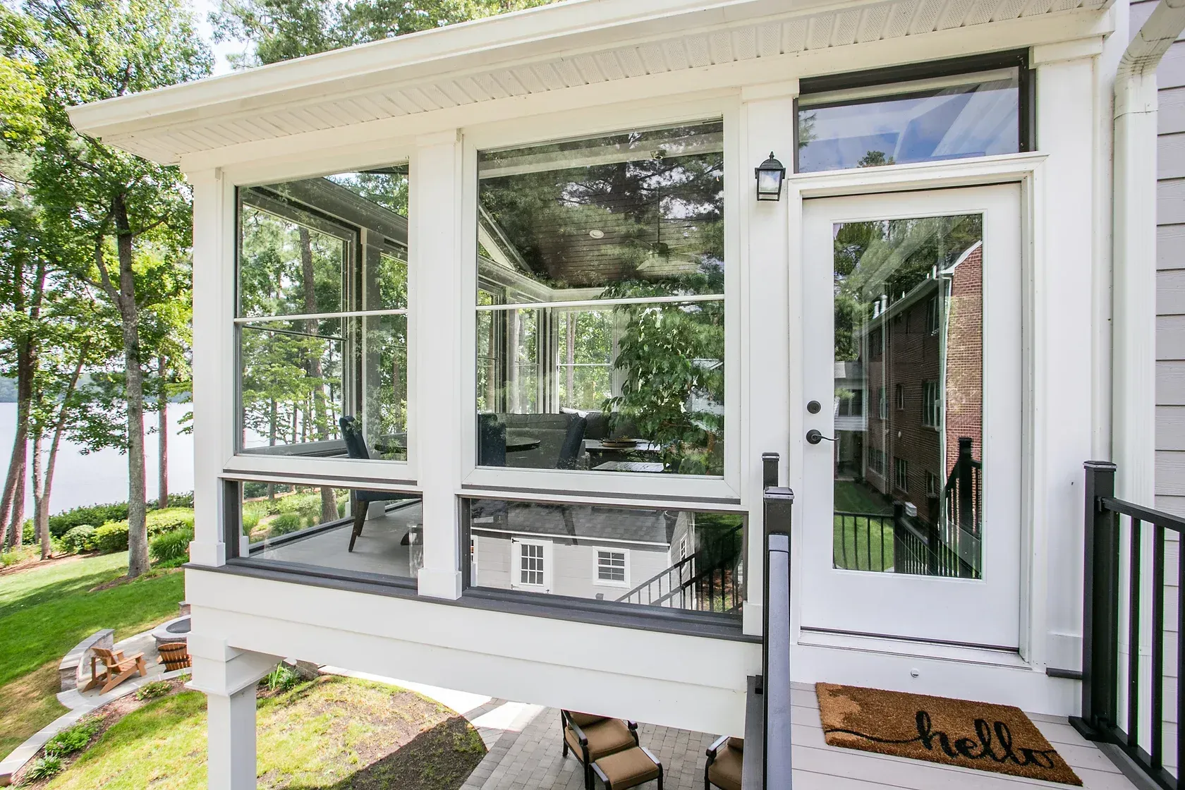 White sunroom with large windows, door, and a black railing.