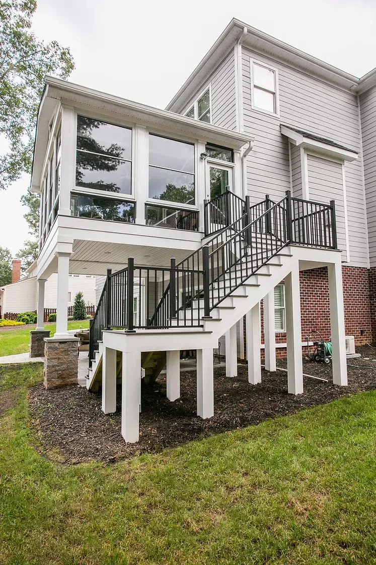 White elevated deck and screened porch attached to a house, with stairs.