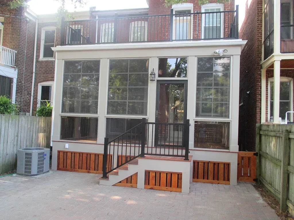 Exterior of a home with a screened-in porch, brick siding, and a small deck with steps, surrounded by fences.