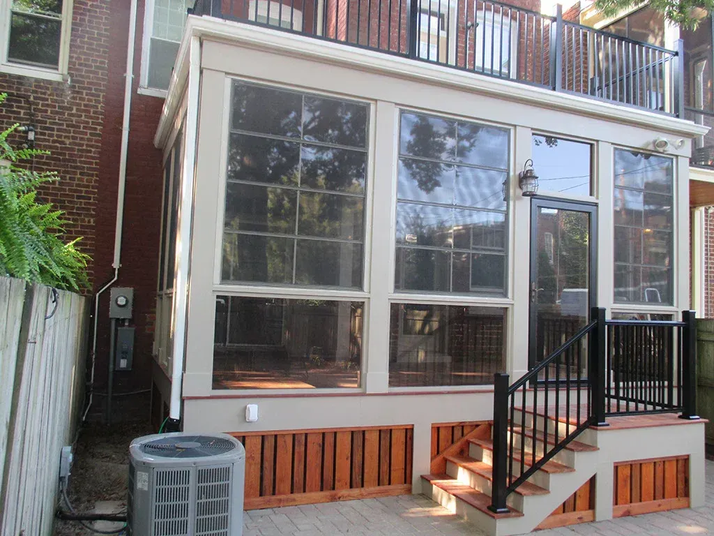 Sunroom addition to a brick building with a small deck and steps. Brown and beige tones.