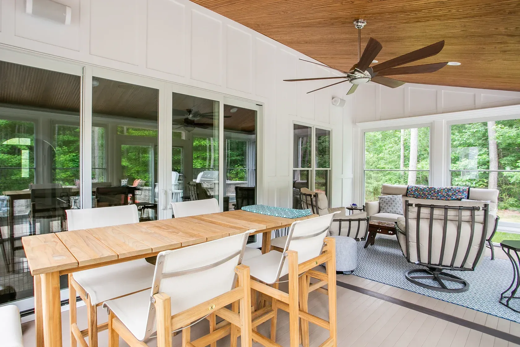Sunroom with a wooden table and chairs, glass doors, and a ceiling fan.