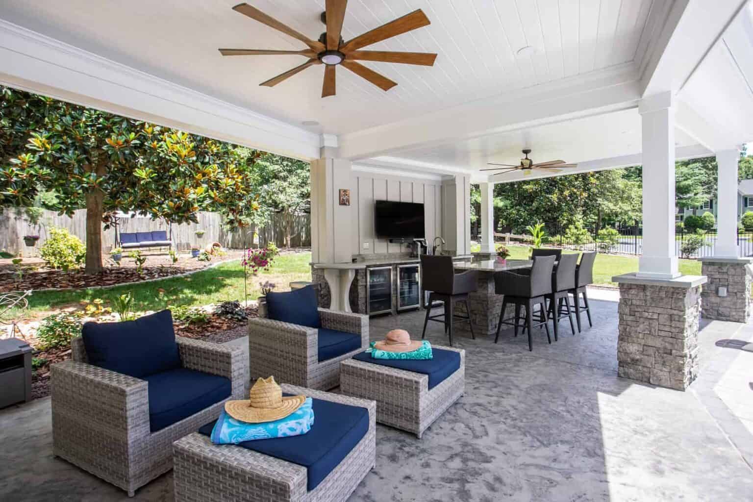 Covered outdoor patio with seating, bar, and television.