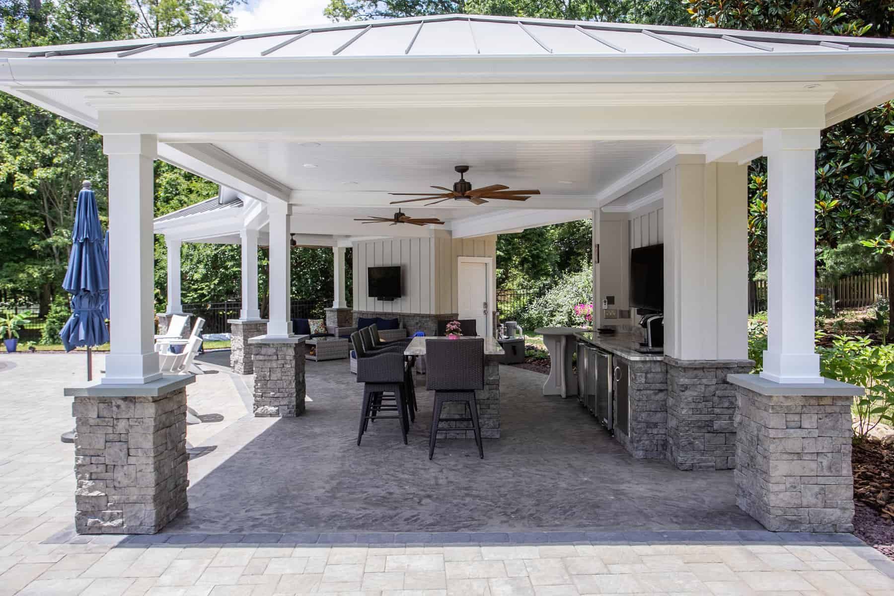 Outdoor covered patio with stone pillars, dining area, and bar.