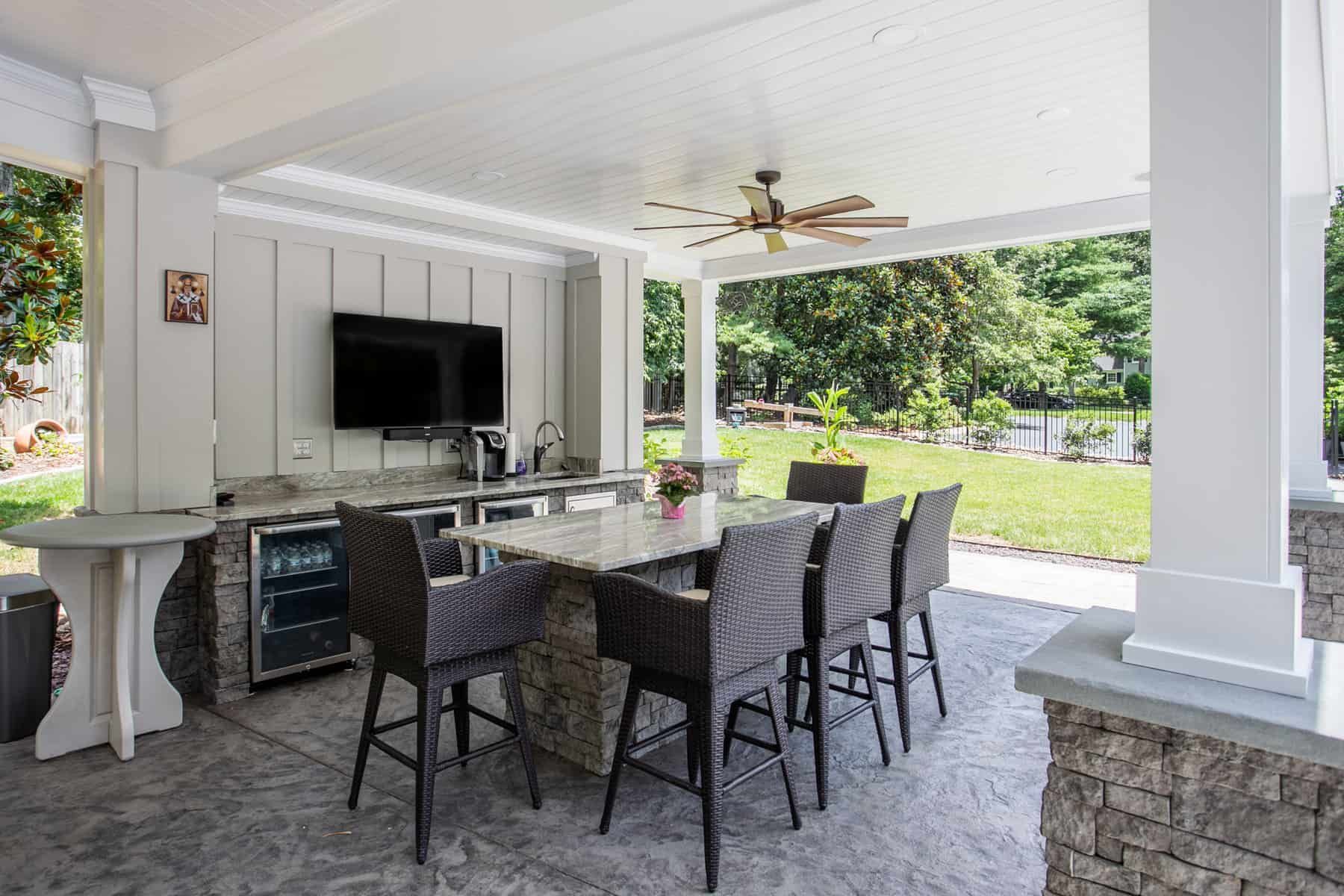 Covered patio with an outdoor kitchen, dining table, and TV.