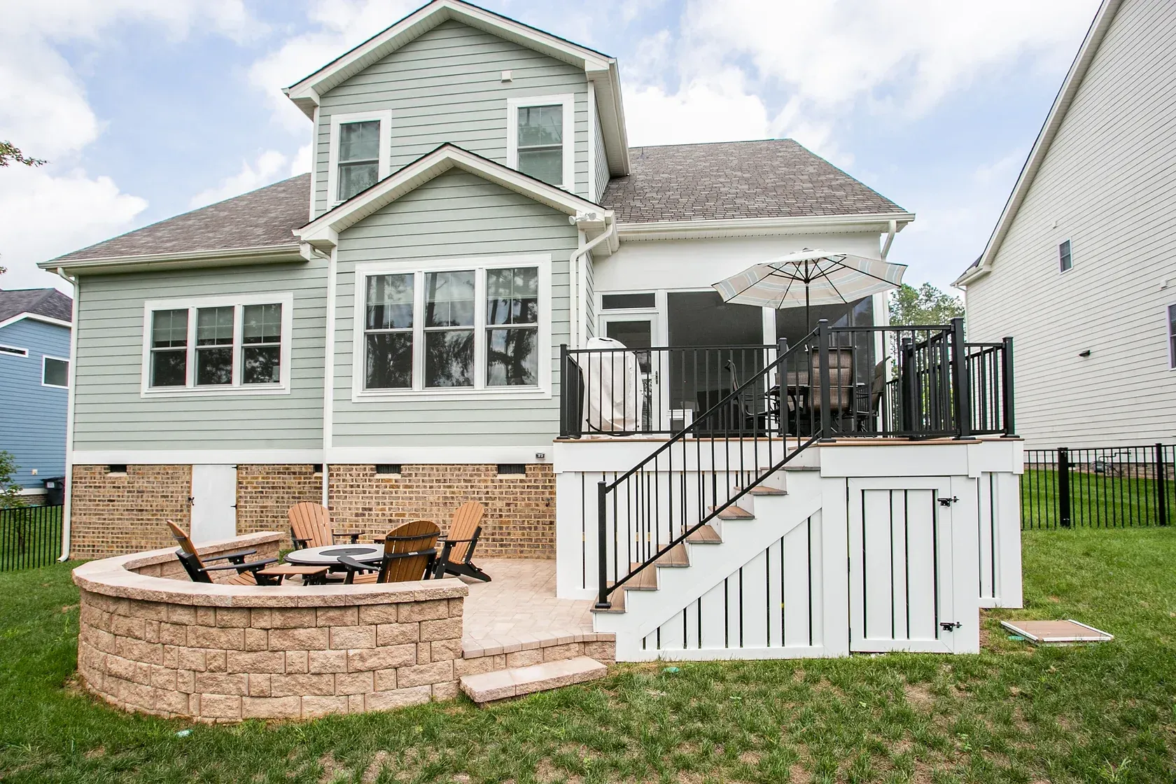 Backyard with house, deck, patio with fire pit, and lawn.