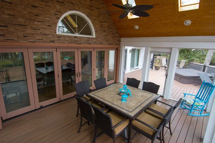 Sunroom with dining table and chairs, adjacent to a deck. Brown, gray, and blue tones.