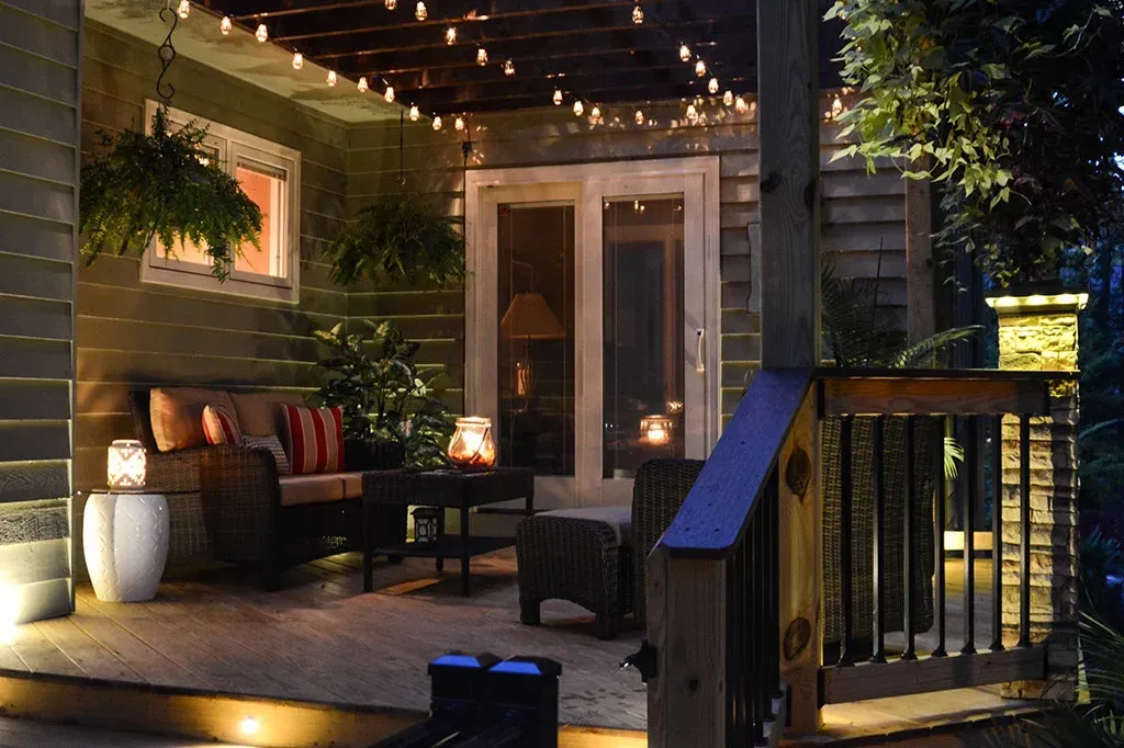 Cozy outdoor patio with string lights, wicker furniture, and lanterns at night.