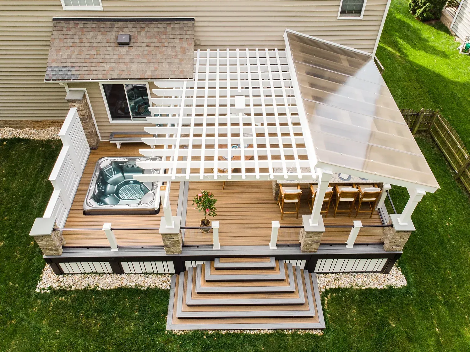 Aerial view of a multi-level deck with a hot tub, pergola, and covered seating area.
