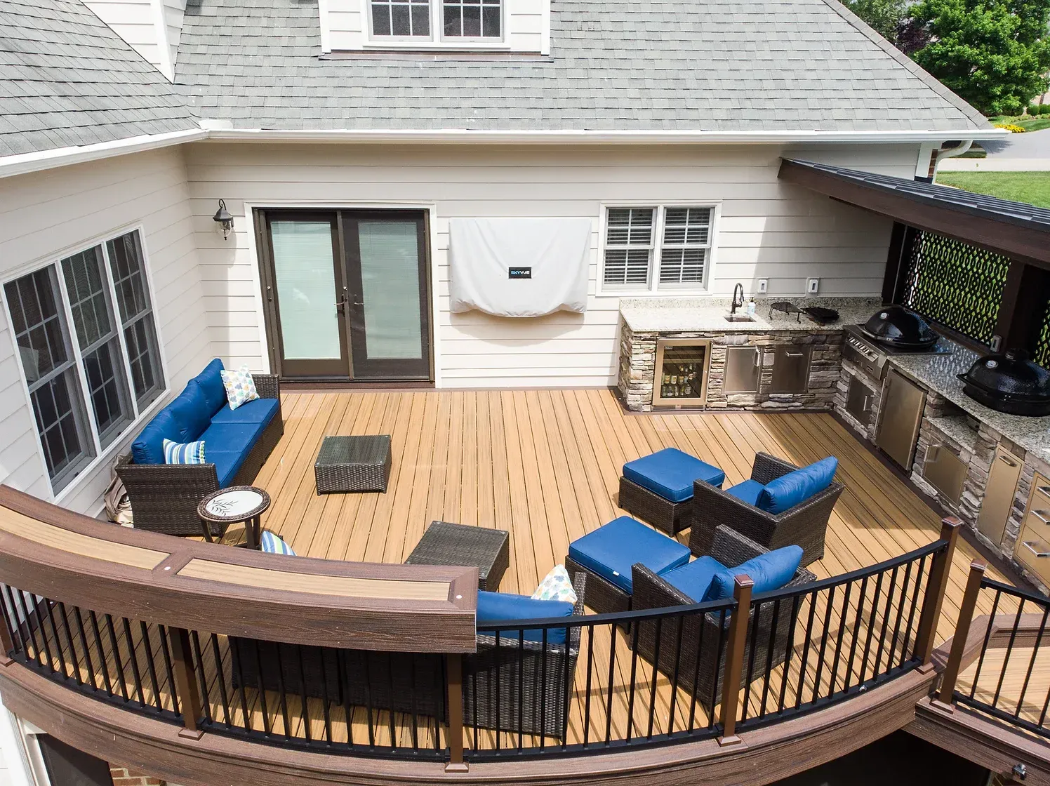 Overhead view of a wooden deck with outdoor kitchen, seating area, and a curved railing.