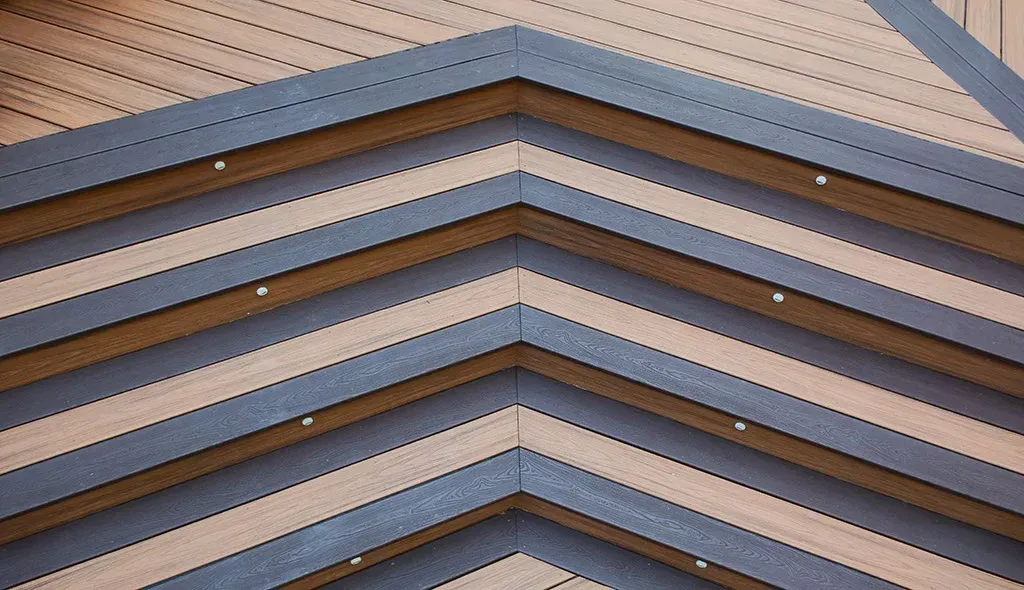 Chevron-patterned building facade, alternating brown and gray triangular panels with evenly spaced circular perforations.
