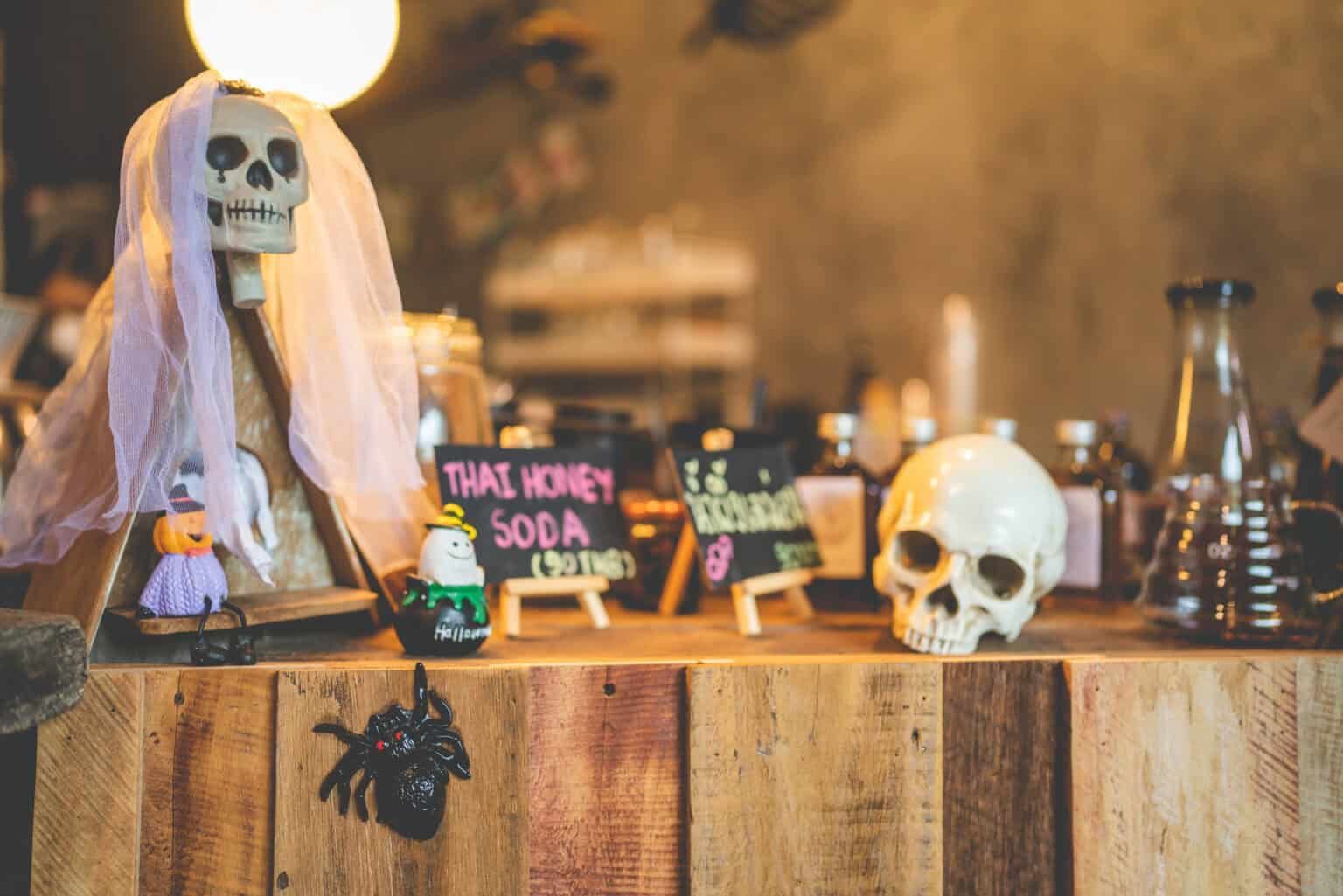 Halloween display: skull with veil, mini signs, decorations on wooden counter.