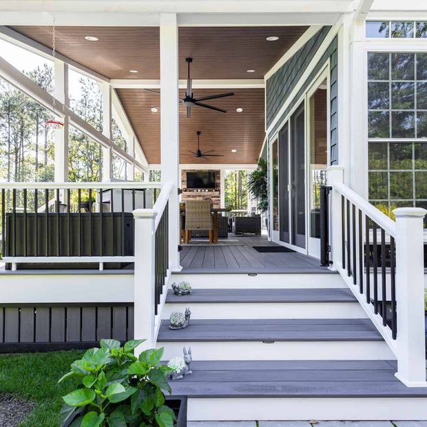 Exterior deck and steps leading to a screened-in porch with seating, ceiling fans, and a fireplace.