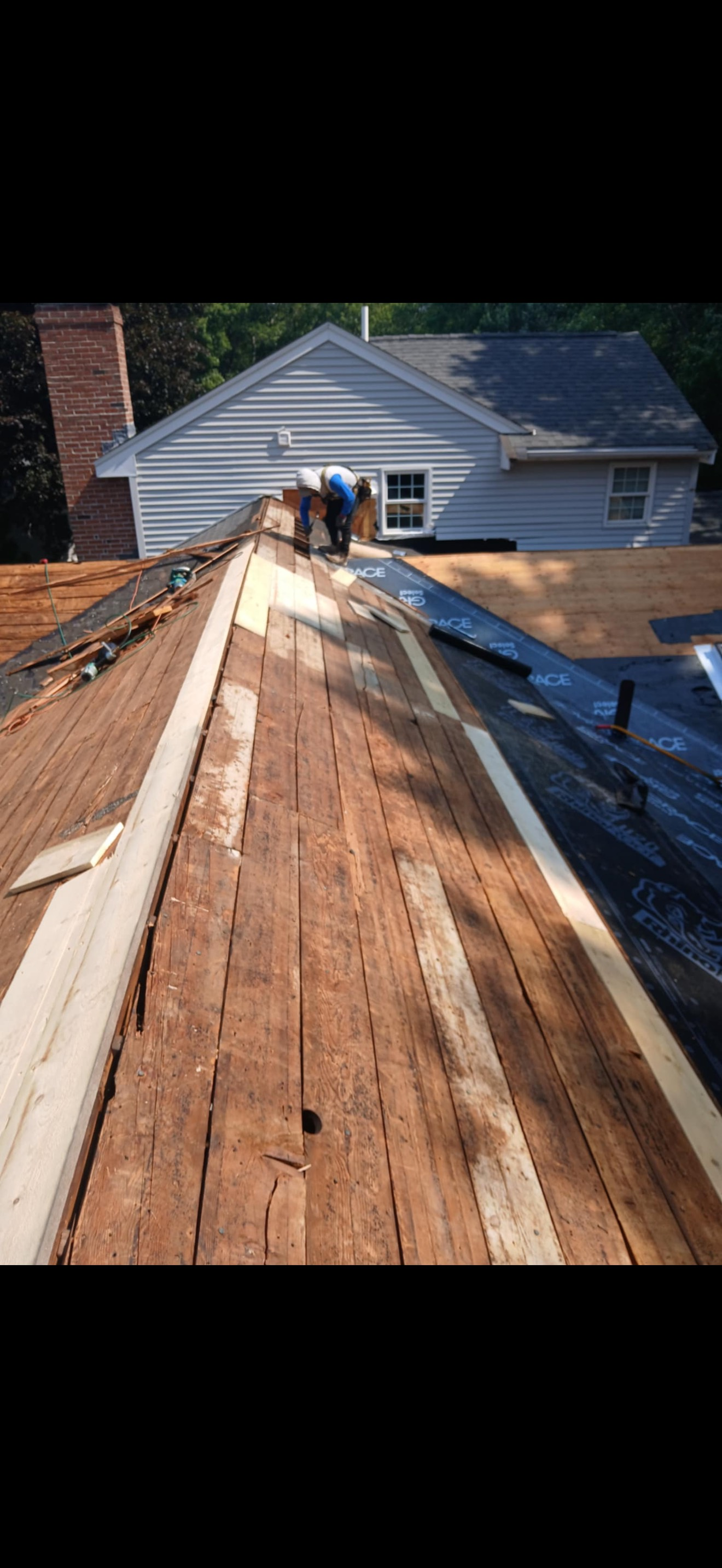 Roofers working on a house roof with exposed wood.
