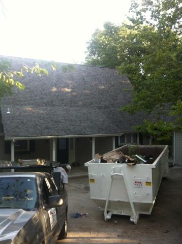 A white dumpster is parked in front of a house