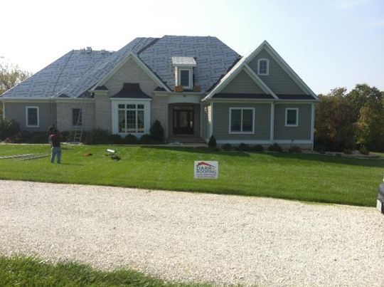 A man is standing in front of a large house with a sign in front of it.