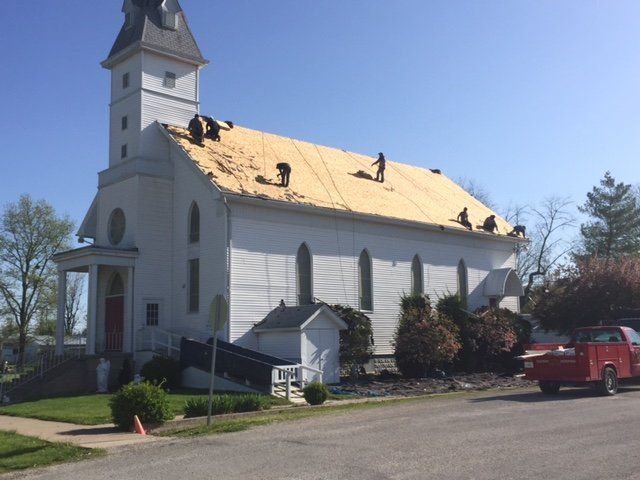 A white church with a red truck parked in front of it.