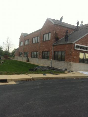 A large brick building with people working on the roof.