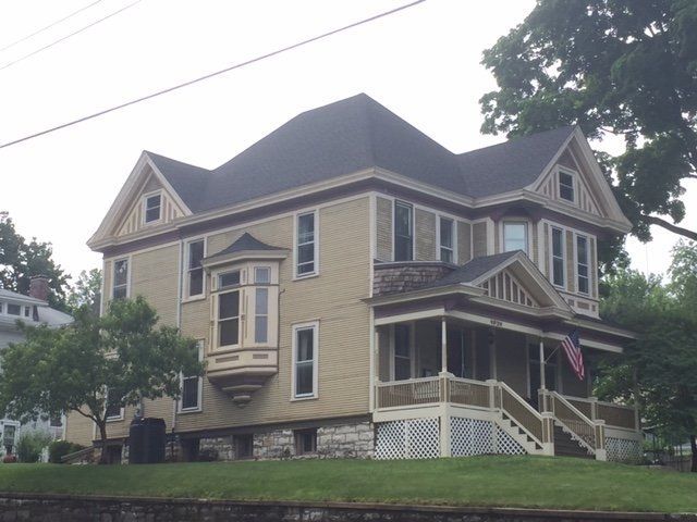 A large yellow house with a black roof