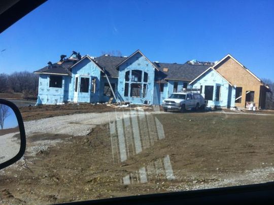 A truck is parked in front of a house under construction