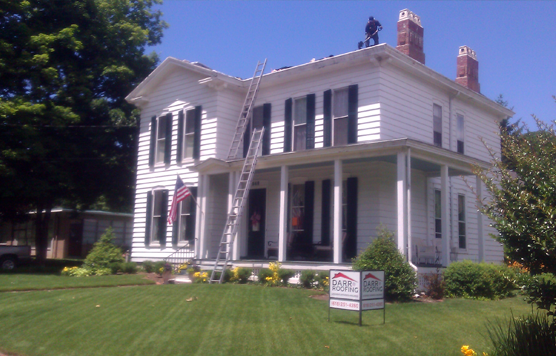 A man is working on the roof of a large white house
