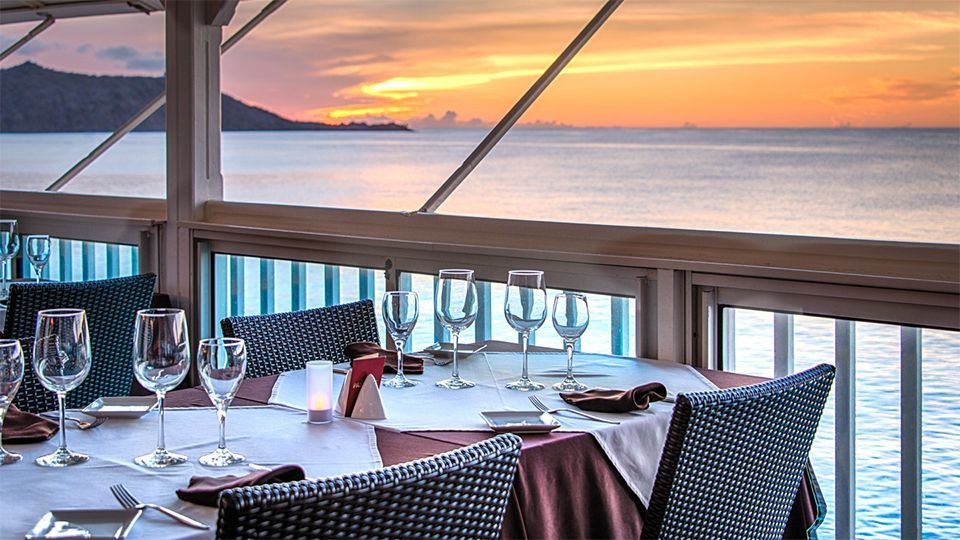 Table set for dinner overlooking the ocean at sunset; champagne flutes, white table cloth.