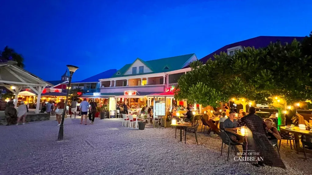 Night scene: outdoor restaurants, people dining, streetlights, blue sky.