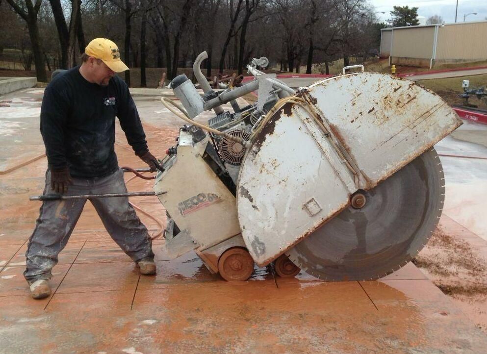 A construction worker is cutting concrete with a circular saw.
