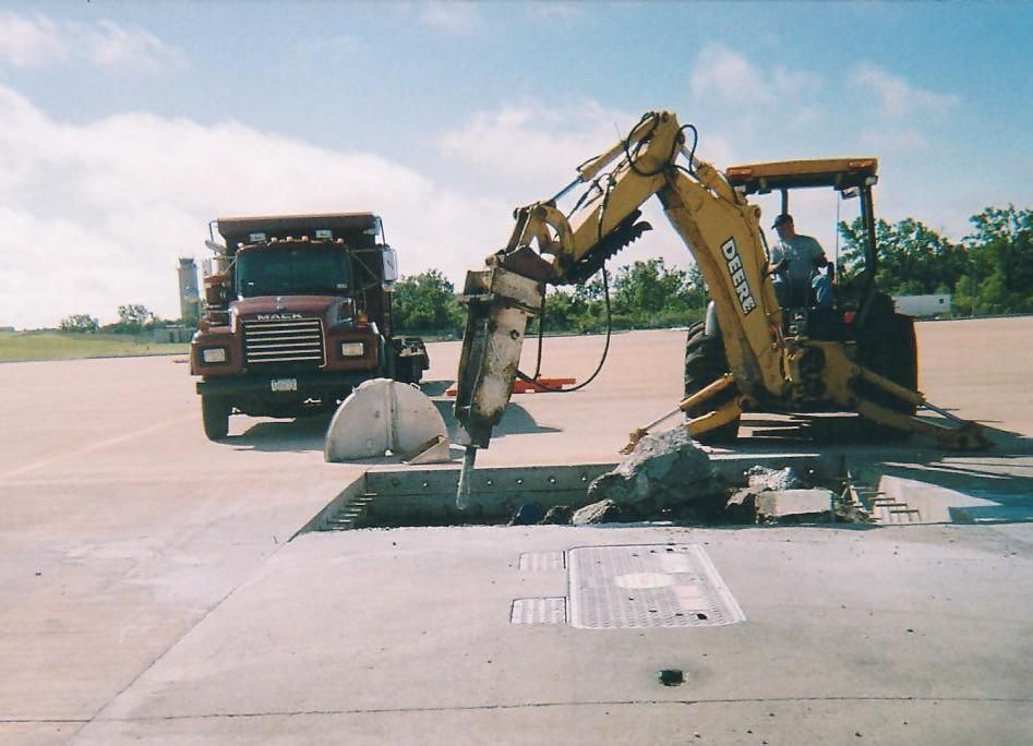 A bulldozer is breaking up concrete on a construction site.
