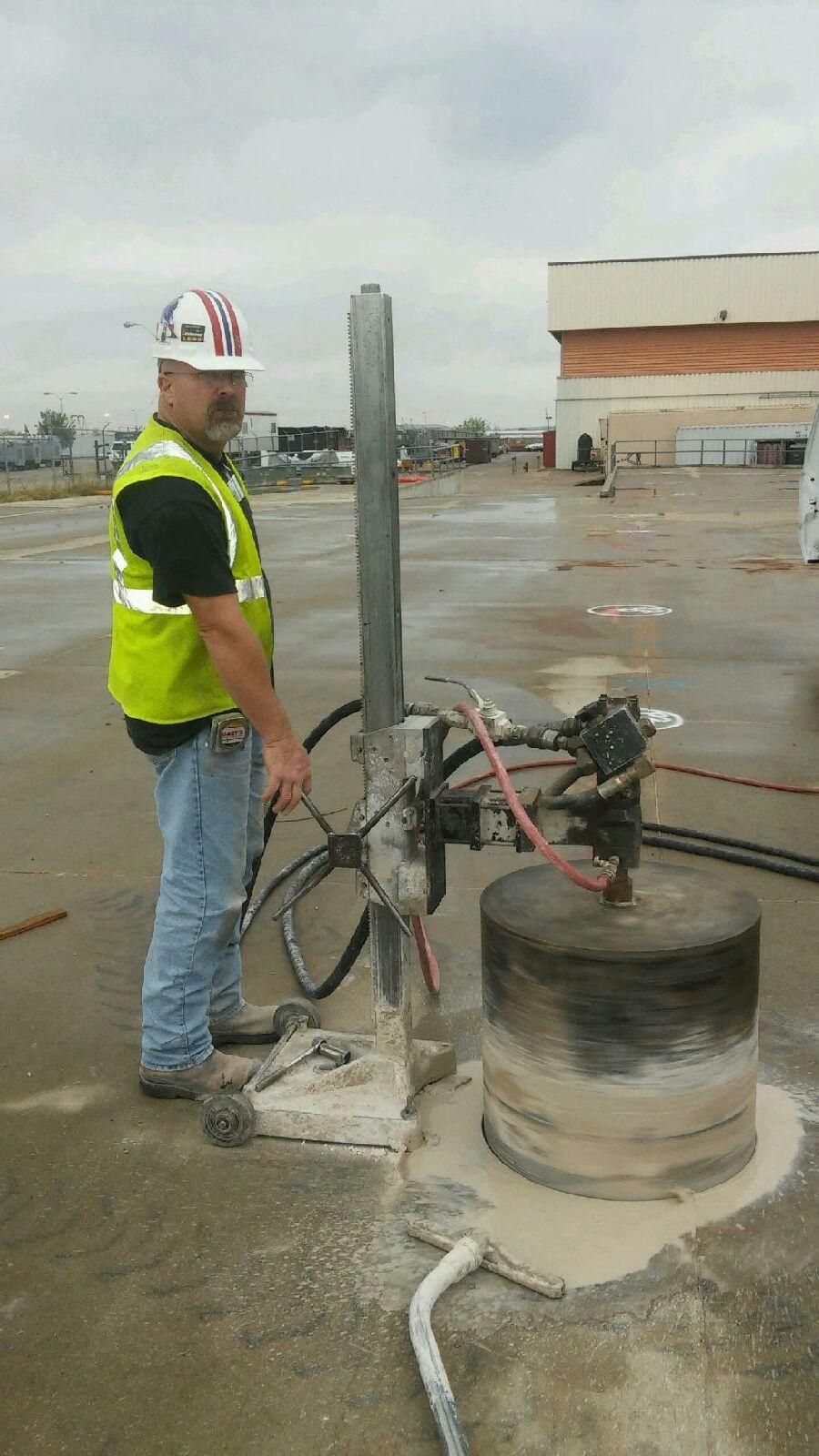 A construction worker is using a machine to cut a hole in a wall.