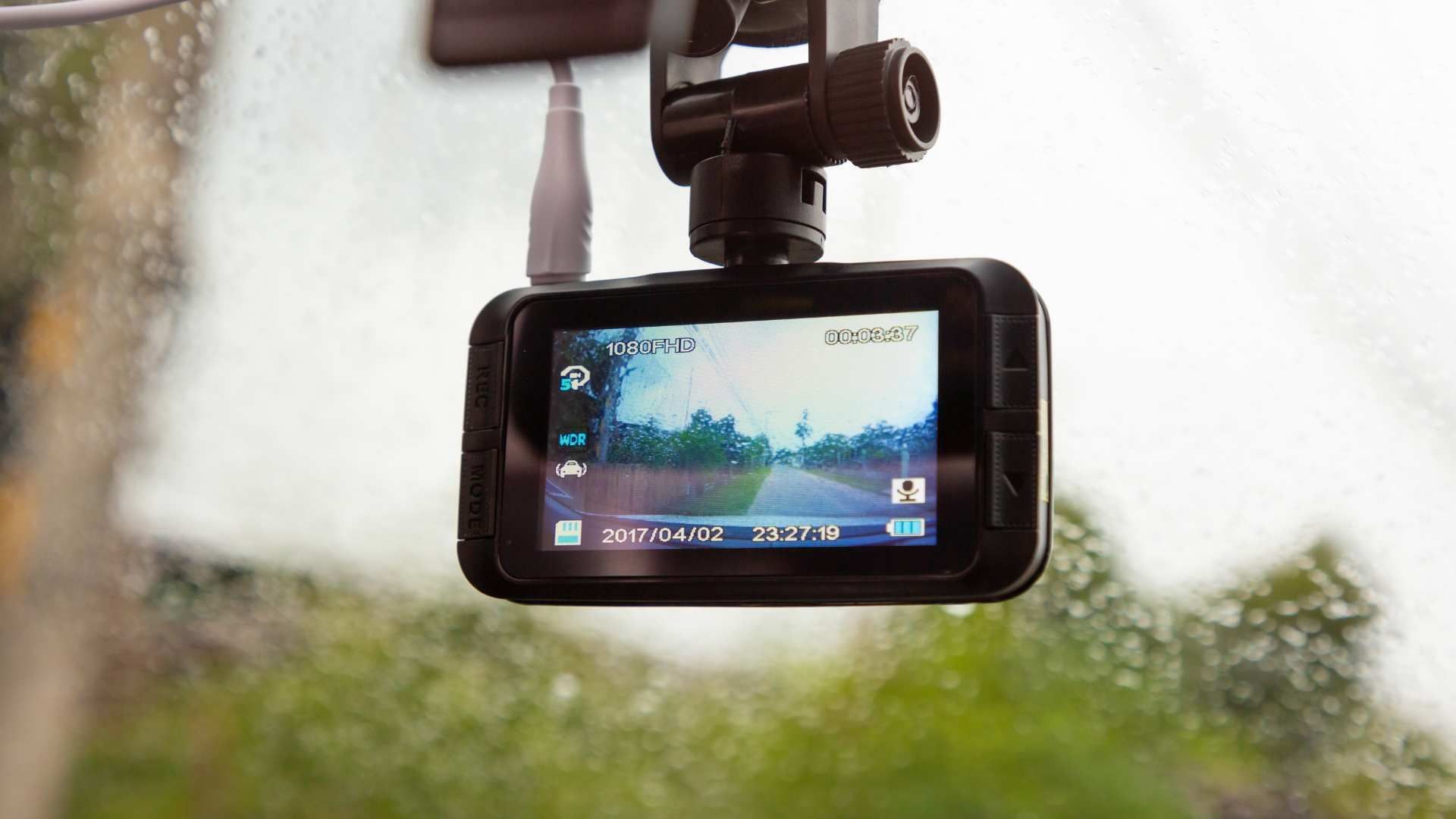Dashcam mounted on a car windshield filming a rainy road ahead