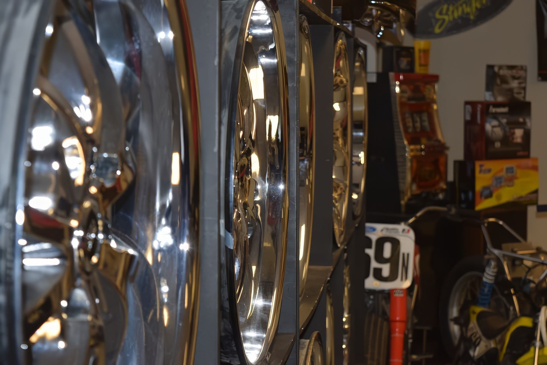 Shiny chrome bicycle wheels and parts in a dimly lit bike shop or garage display
