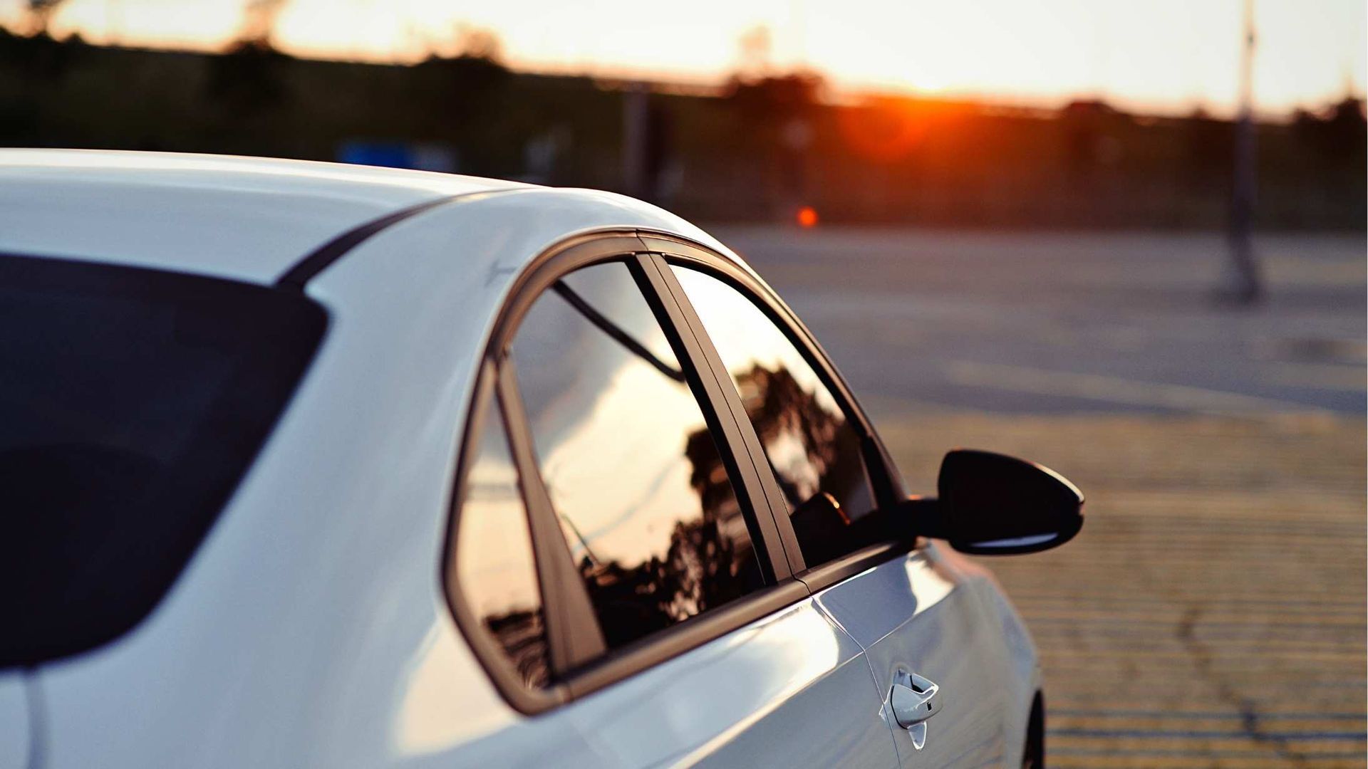 White car parked at sunset with warm reflections in the side windows