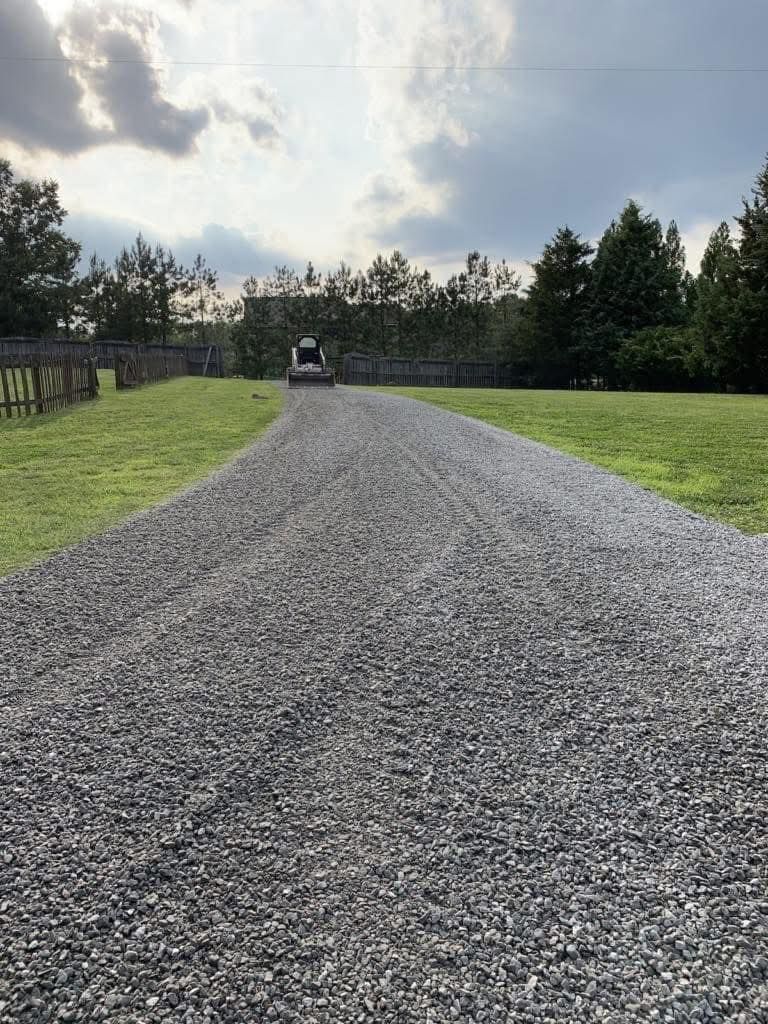 A gravel road going through a grassy field.