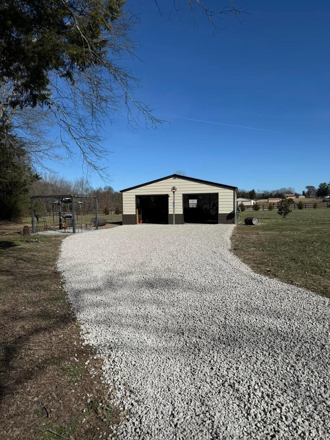 There is a gravel driveway leading to a barn.