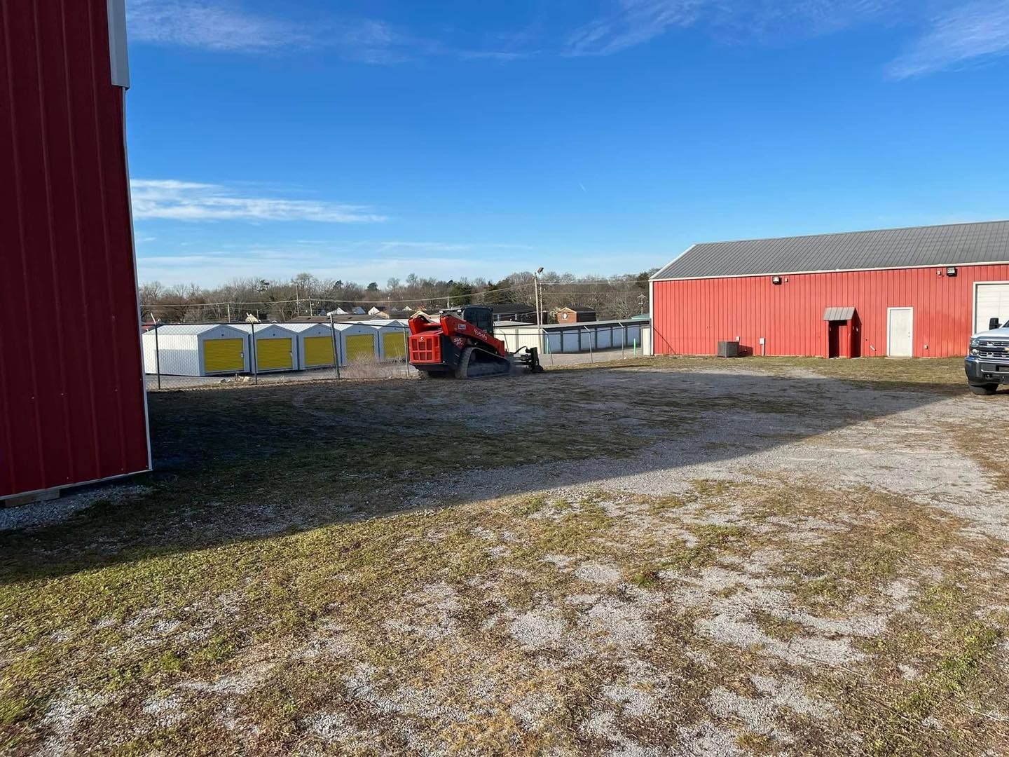 A red barn with a tractor parked in front of it.
