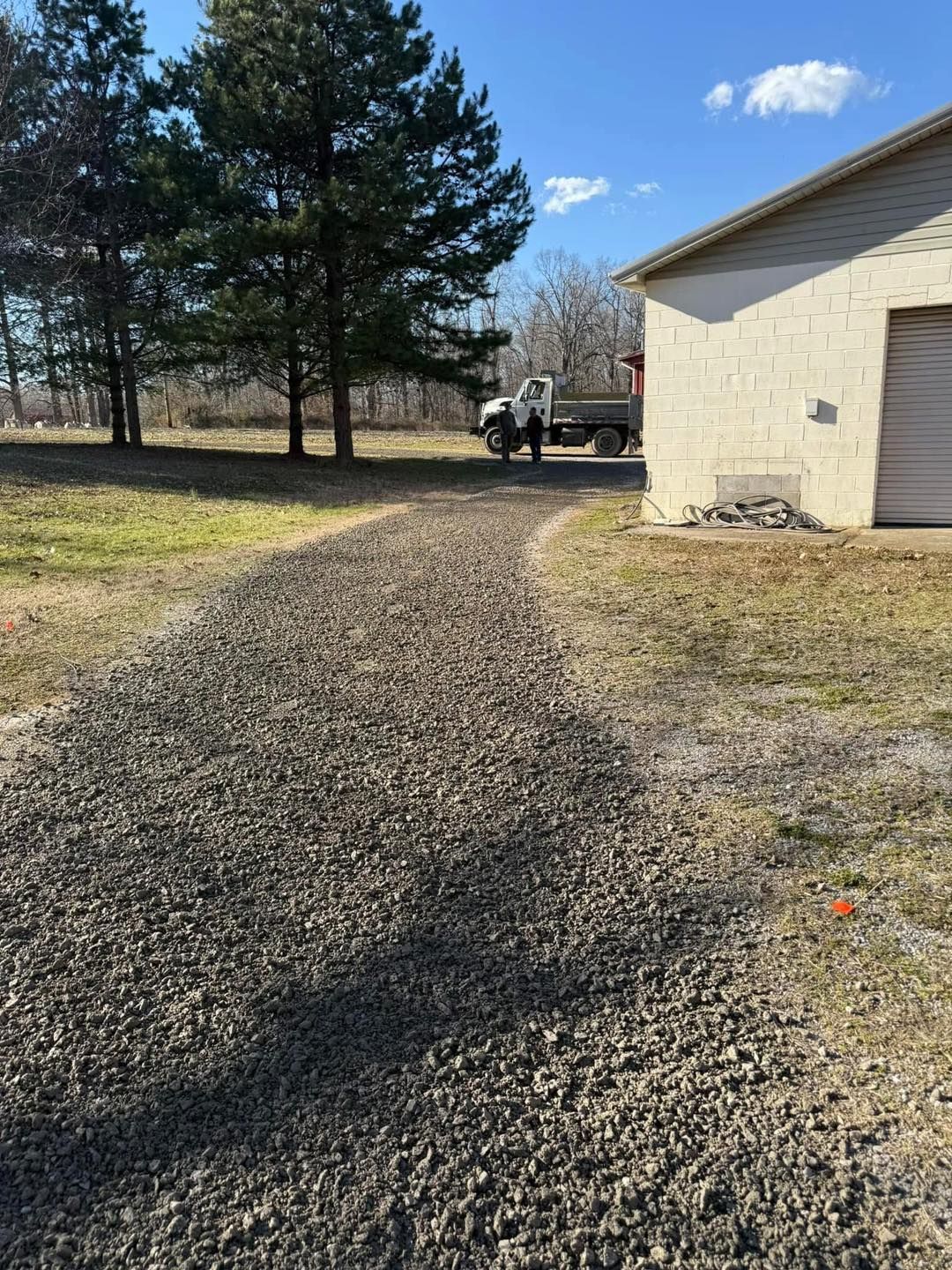 A truck is parked in a gravel driveway next to a garage.