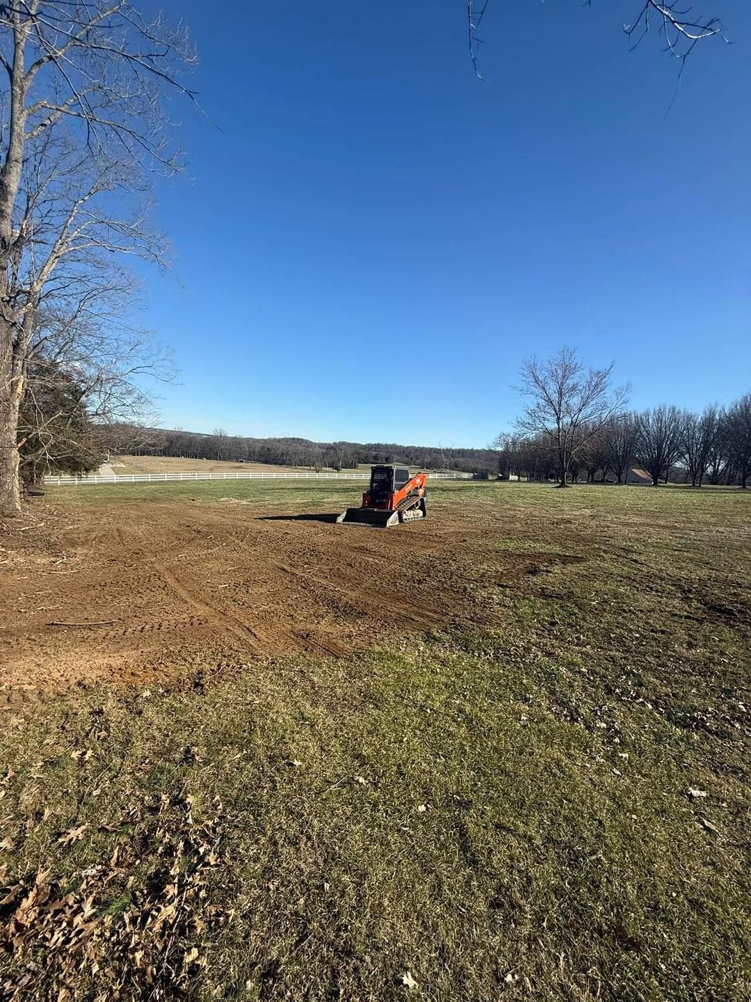 A tractor is driving through a grassy field on a sunny day.