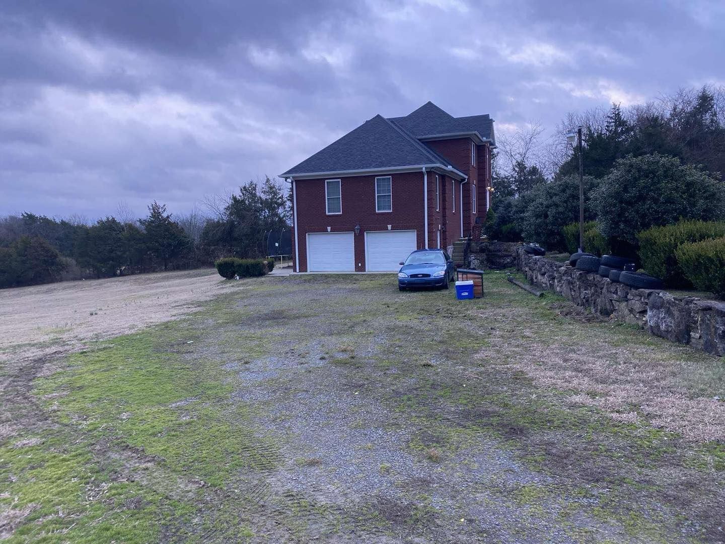 A large red house with a blue car parked in front of it.