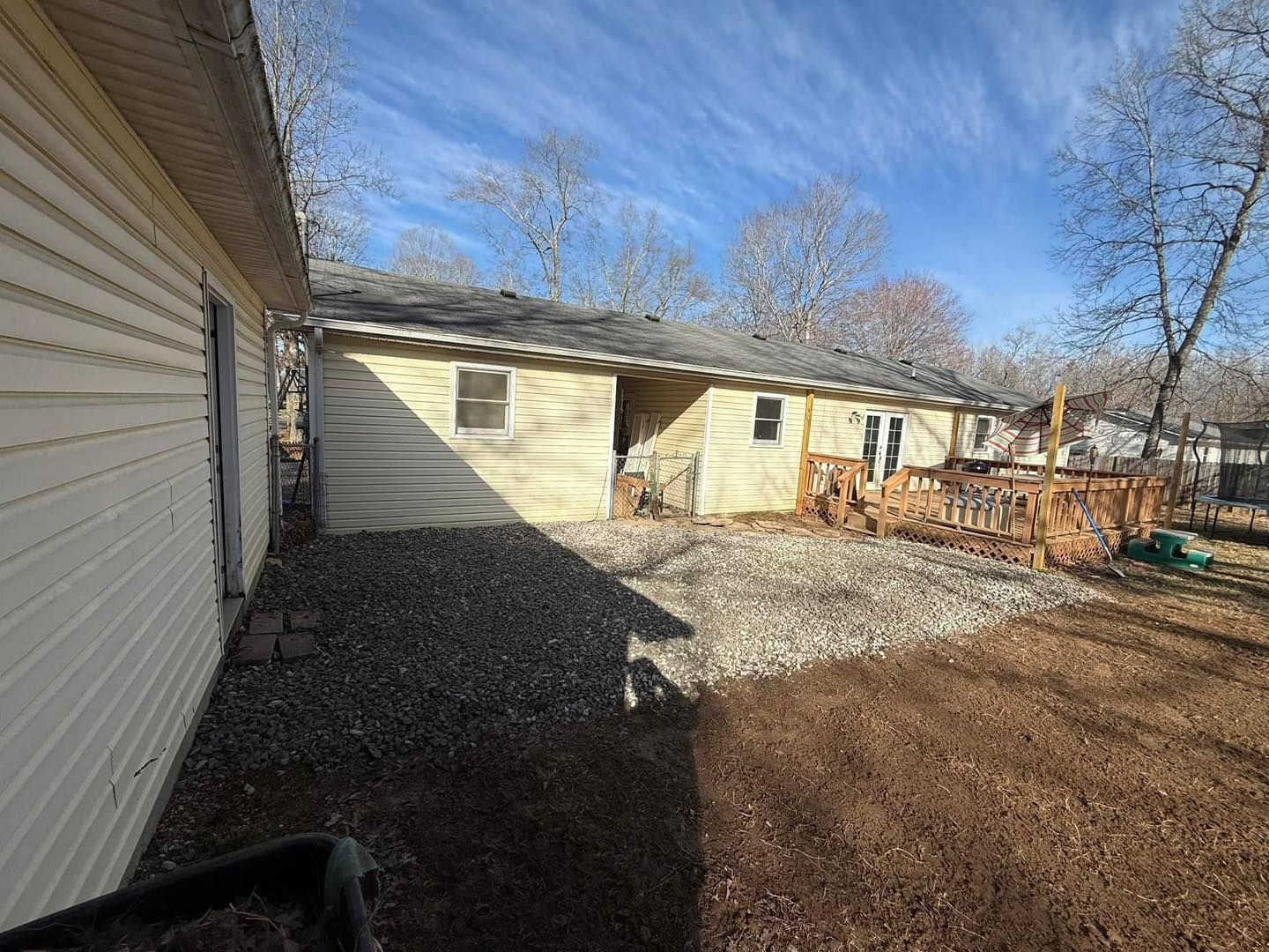 The backyard of a house with a gravel driveway and a garage.
