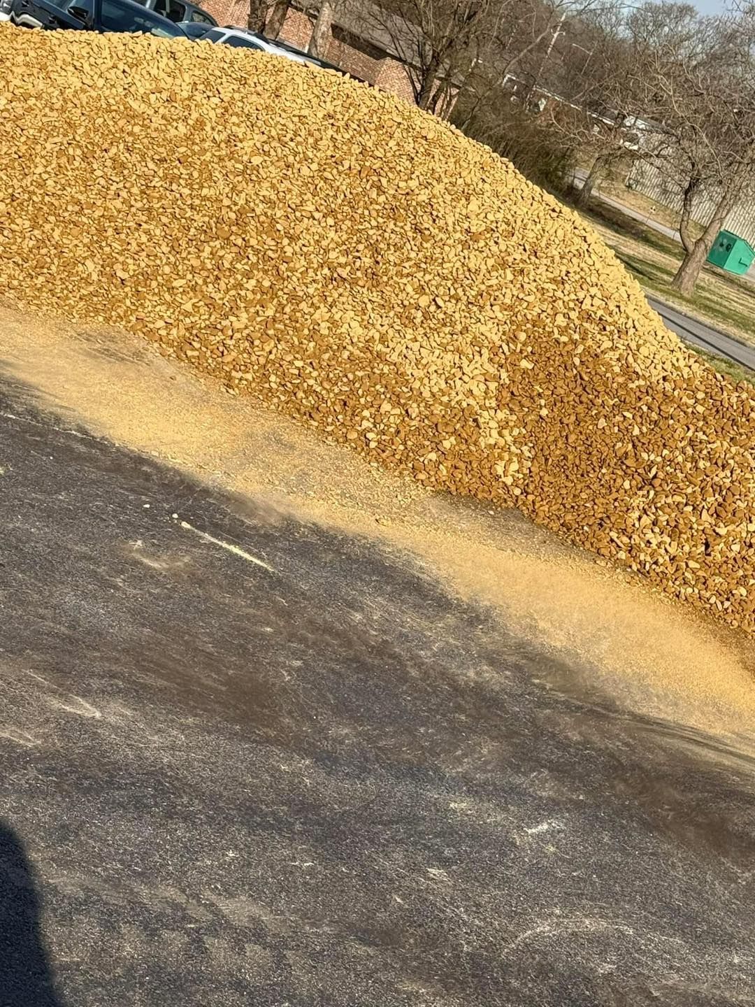 A large pile of wood chips is sitting on the side of a road.