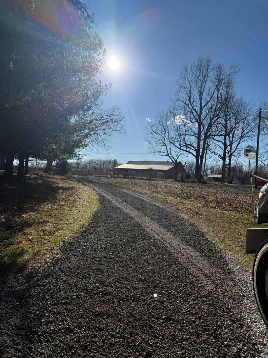 The sun is shining brightly on a gravel road.