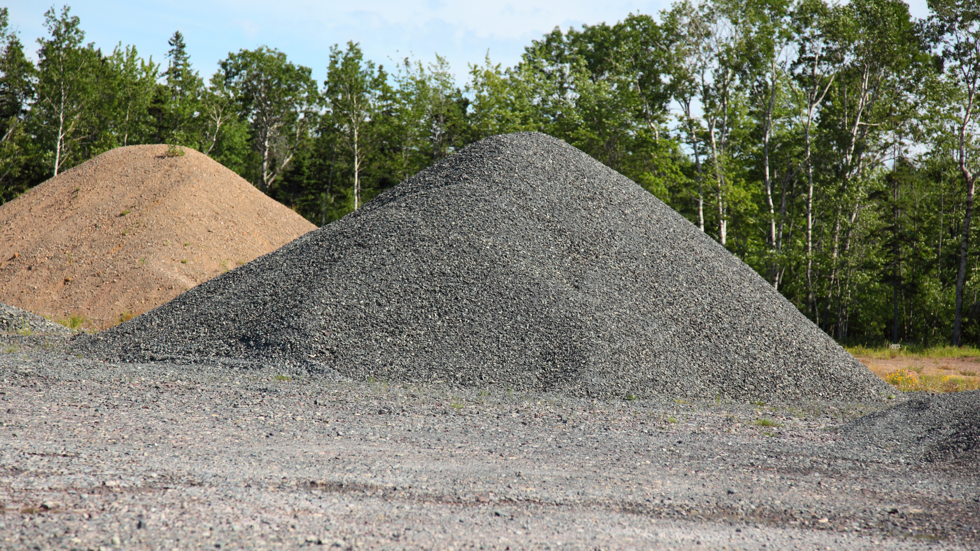 Two piles of gravel are stacked on top of each other in a field.