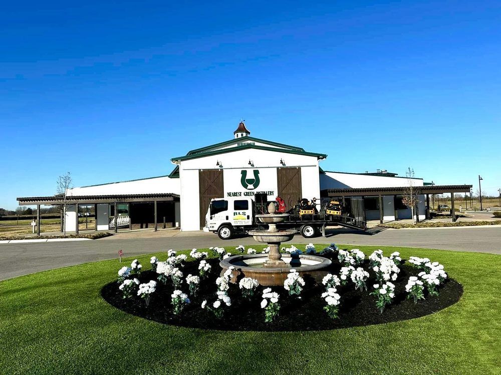 A horse barn with a truck parked in front of it.