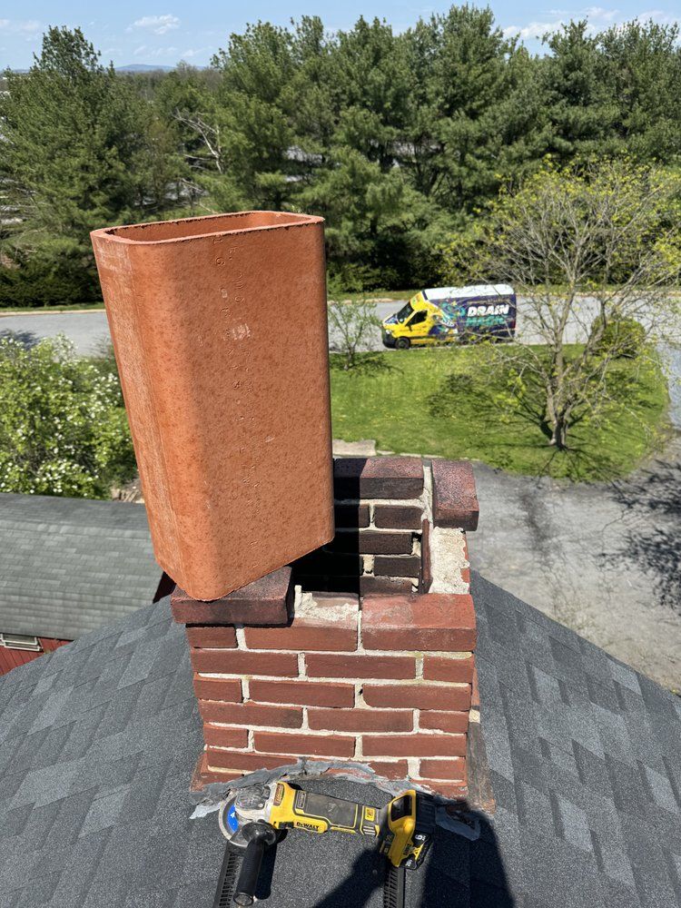 Chimney being repaired, brick and metal work visible. A yellow work truck is in the background.