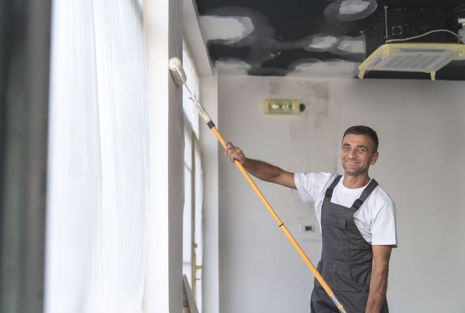 A man is painting a wall with a paint roller.