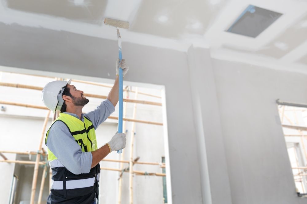 A man is painting a ceiling with a roller.